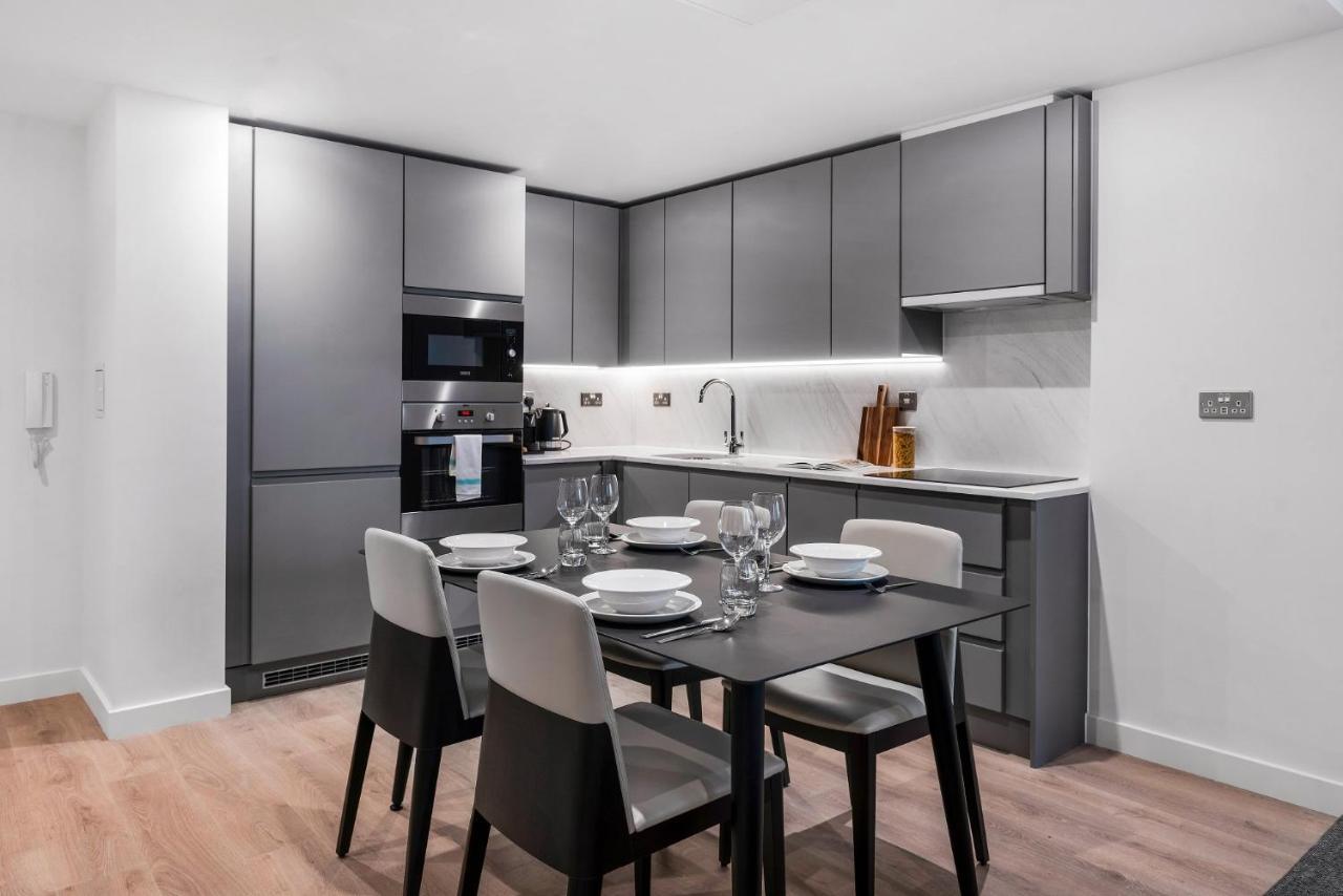 Citysuites 2 Aparthotel Manchester Kültér fotó The photo shows a modern kitchen and dining area. The kitchen features sleek, gray cabinetry and a countertop that complements the overall aesthetic. There are built-in appliances, including an oven and refrigerator, arranged neatly. Next to the kitc