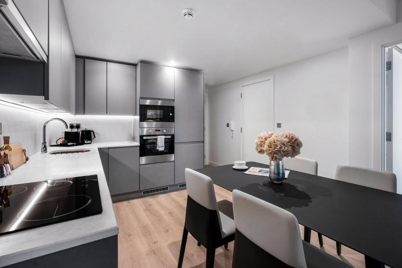 Citysuites 2 Aparthotel Manchester Kültér fotó The photo shows a modern kitchen and dining area. The kitchen features sleek gray cabinets, a countertop with an embedded cooktop, and built-in appliances, including an oven and microwave. There’s a small coffee maker on the counter. Adjacent to the 