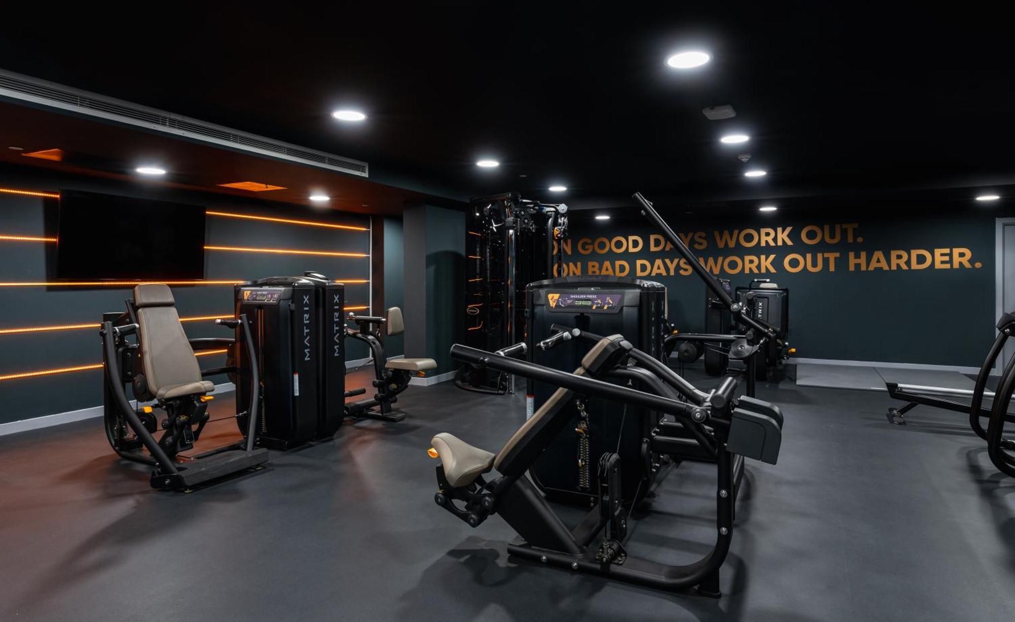 Citysuites 2 Aparthotel Manchester Kültér fotó The photo shows a modern gym interior. The gym features various exercise machines, including weight training equipment. The flooring is dark, and the walls are adorned with motivational text that reads, "ON GOOD DAYS WORK OUT. ON BAD DAYS WORK OUT HA